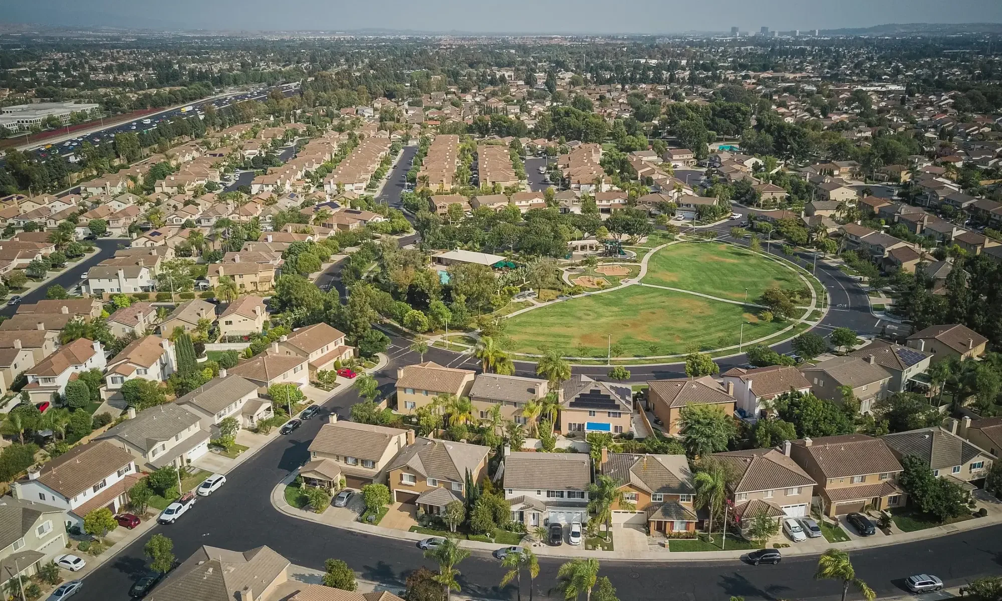 Aerial view of suburban homes and rooftops around a park