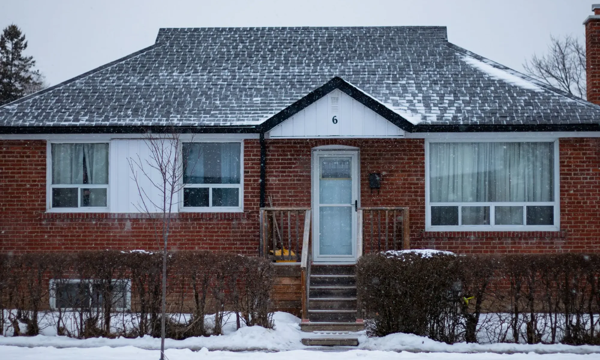 Brick bungalow with a snow covered roof in winter