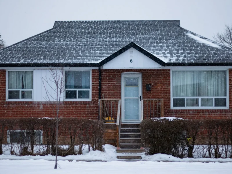 Brick bungalow with a snow covered roof in winter