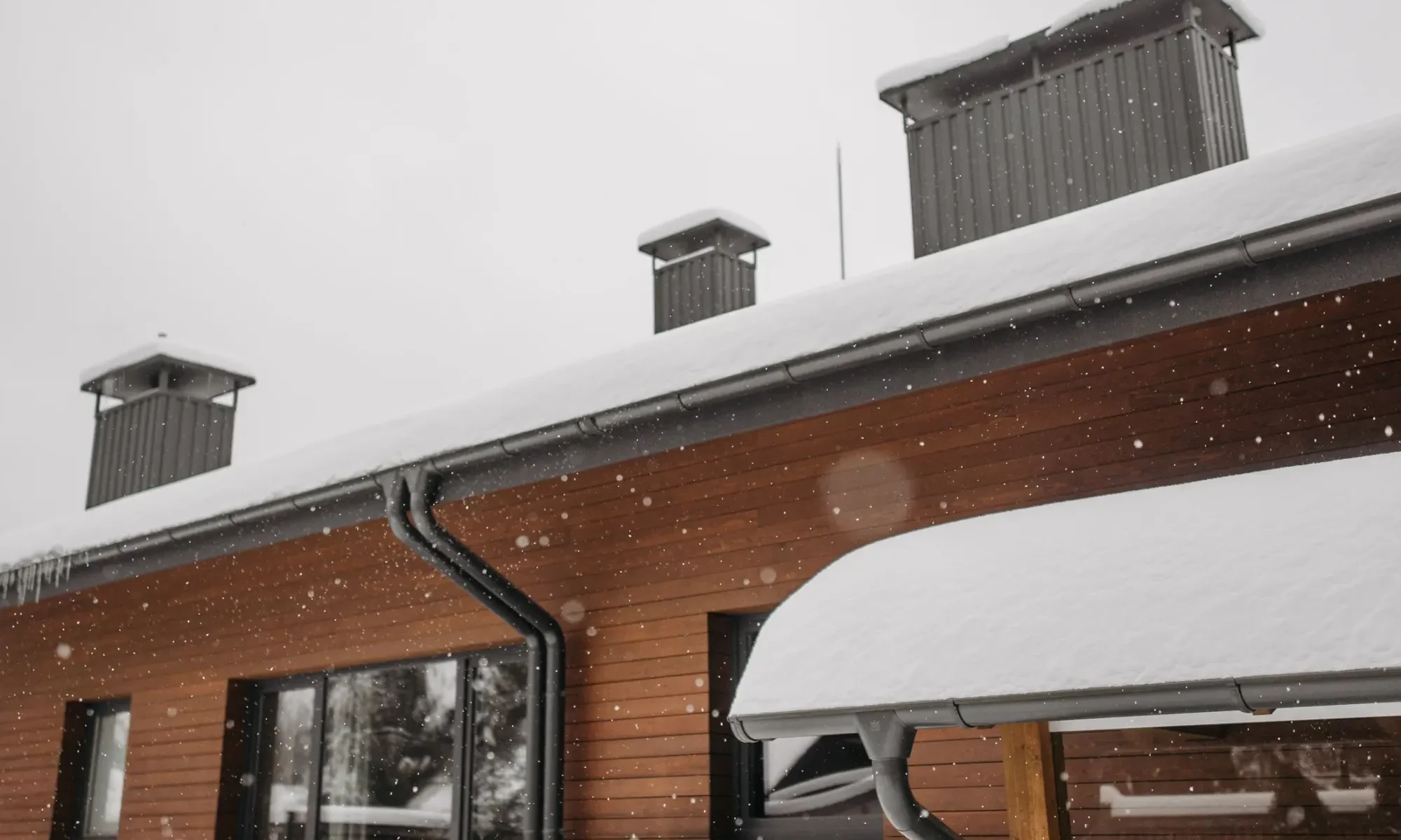 Eavestrough and downspout along the roofline of a home in winter
