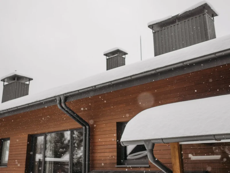 Eavestrough and downspout along the roofline of a home in winter