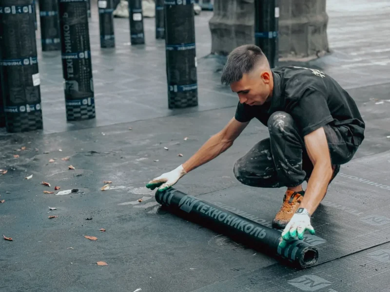 Roofer rolling out a membrane on a flat roof