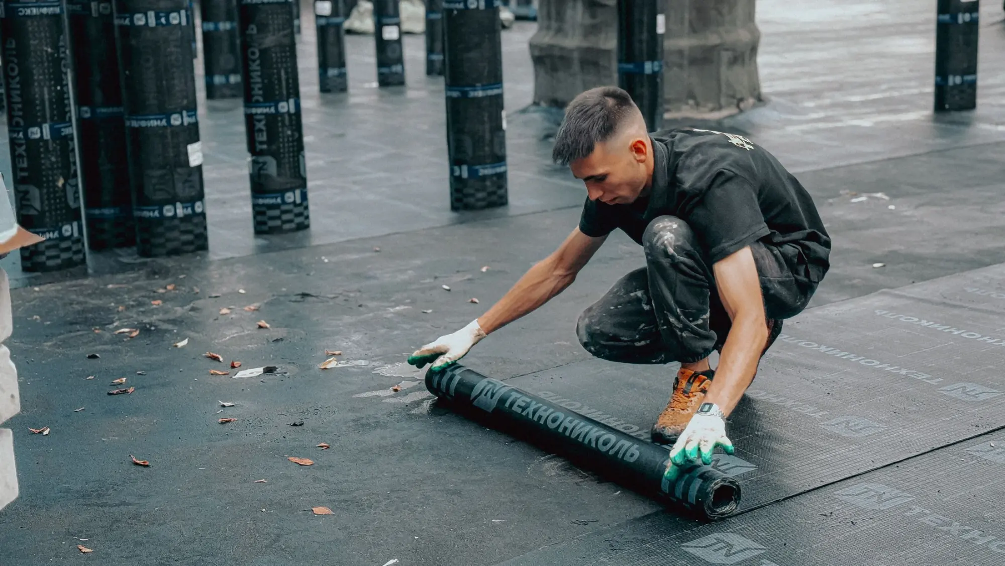 Roofer rolling out a membrane on a flat roof