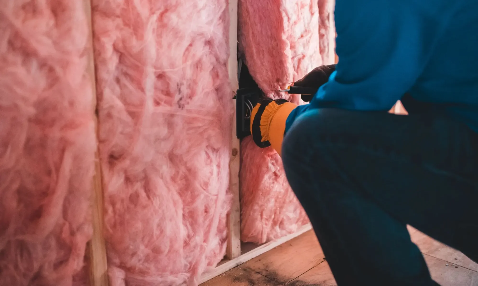 Installer fitting insulation batts between framing