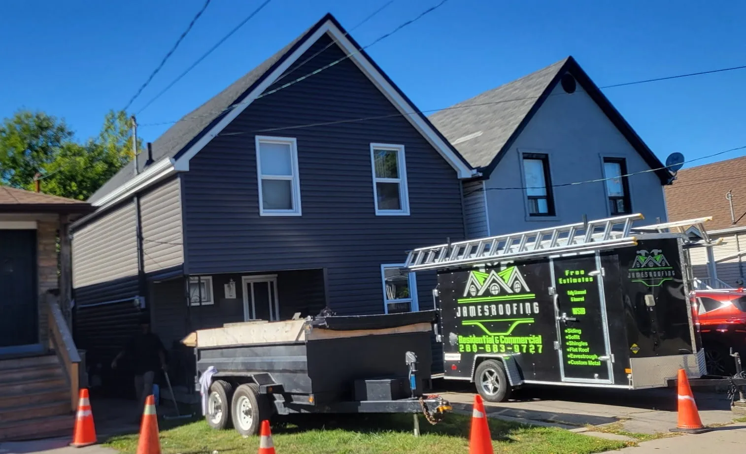 James Roofing branded trailer and dump trailer outside a home with new dark grey siding and a new shingle roof