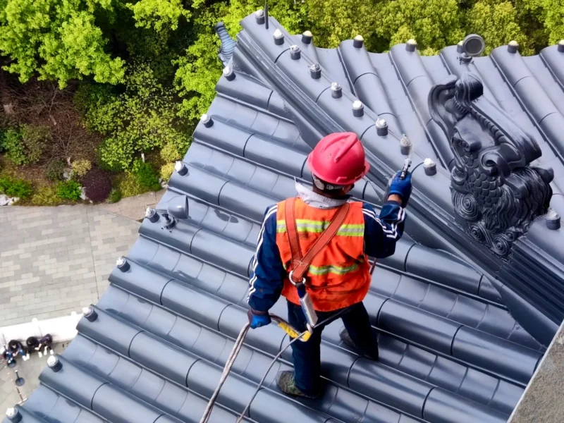 Roofer in safety gear inspecting a roof