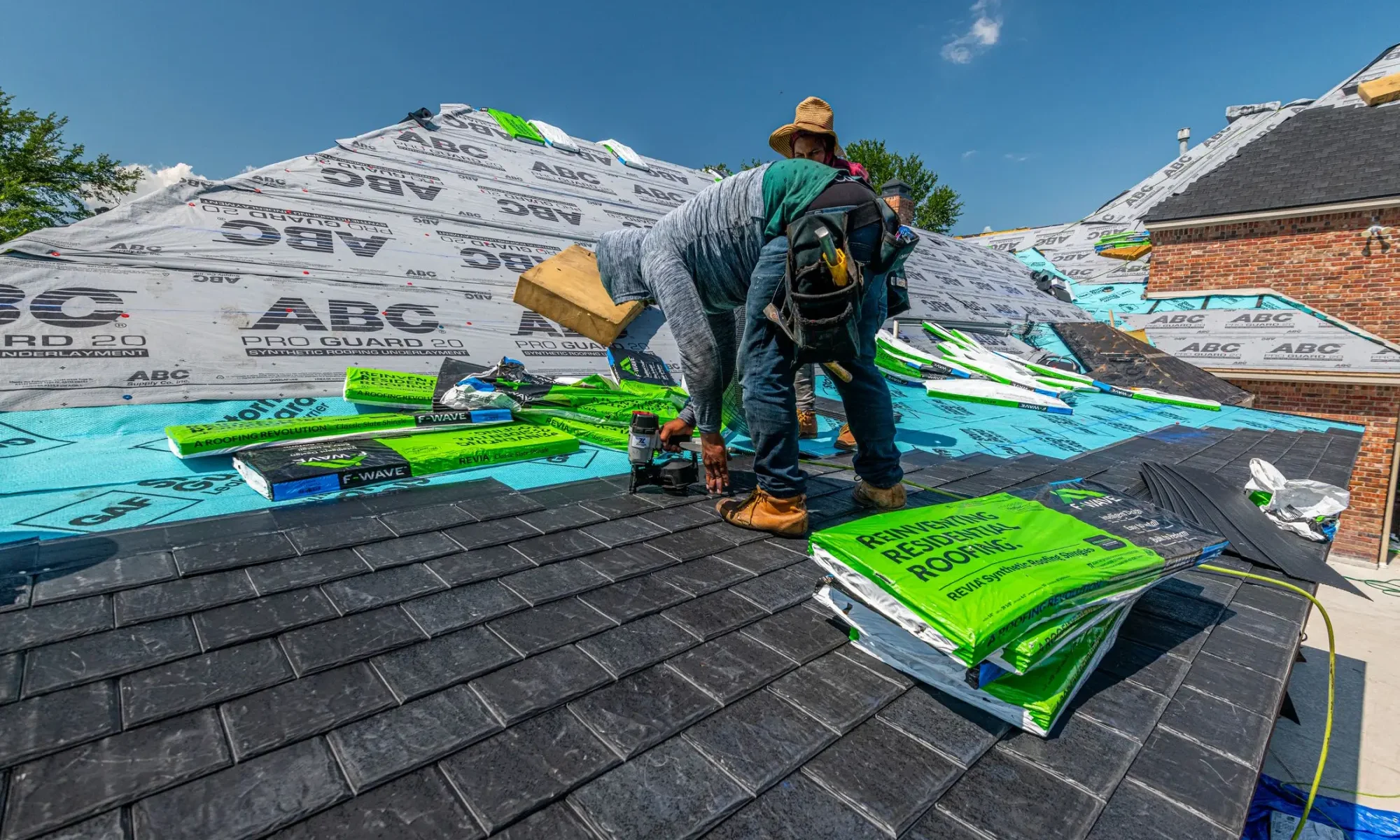 Roof replacement crew installing new shingles over synthetic underlayment