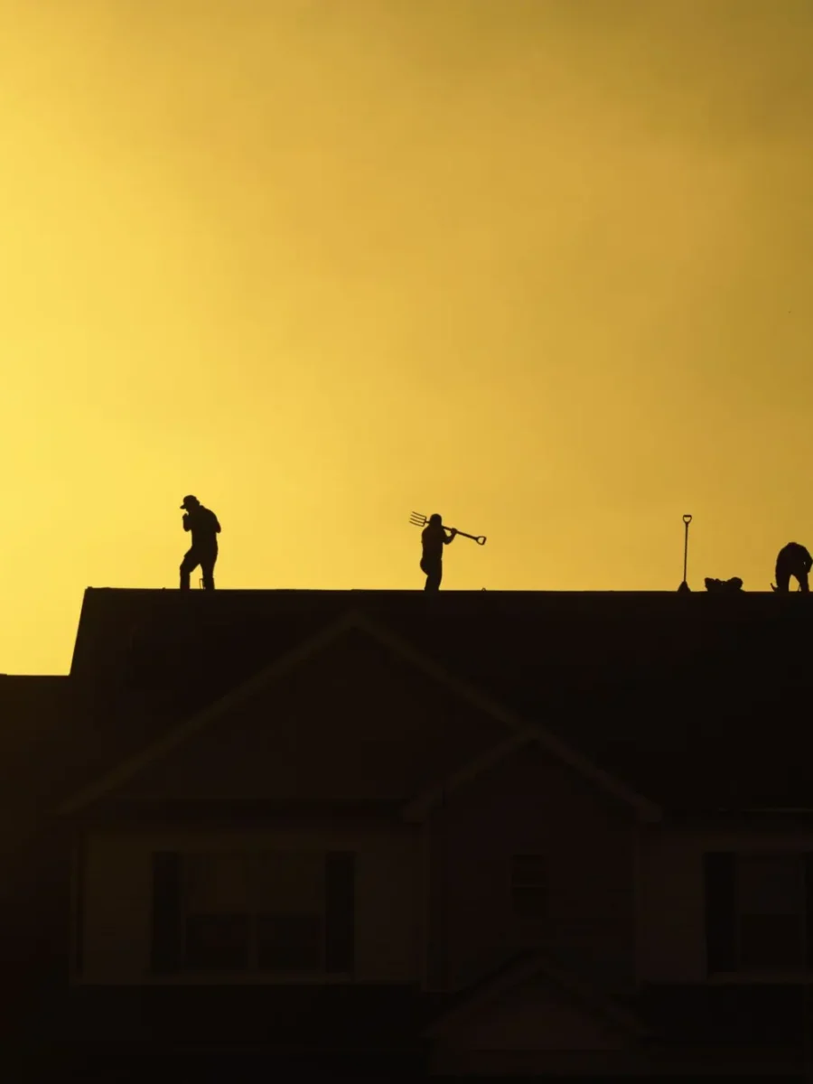 Roofers working on a house roof at sunset